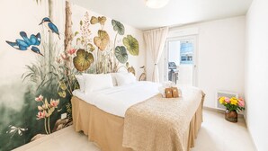Ein Hotelzimmer mit einem Bett, einer großen Wandmalerei, einem Fenster und einem kleinen Tisch mit Handtüchern.