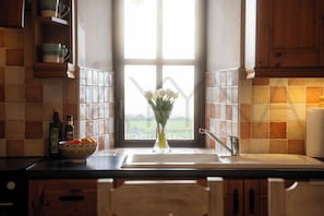 Eine Küche mit Fenster, einer Obstschale und einem Blumenstrauß.