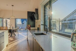 Eine moderne Küche mit großem Fenster, einem Essbereich und Blick ins Freie.