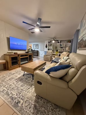 A living room with a television, a ceiling fan, a sofa, a coffee table, and a patterned rug. - Harris chain Lake House Hideaway (Tavares)