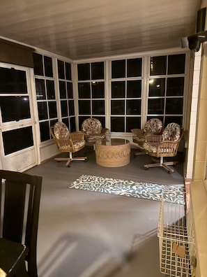 A corner room with large windows, wicker chairs, a round coffee table, and a patterned rug. - Harris chain Lake House Hideaway (Tavares)