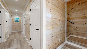A hallway with wooden panel walls, white doors, and a light-colored floor. - CL5 Shared Pool, Charcoal Grill, Old Town Port A (Port Aransas)
