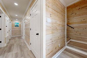 A hallway with wooden panel walls, white doors, and a light-colored floor. - CL5 Shared Pool, Charcoal Grill, Old Town Port A (Port Aransas)