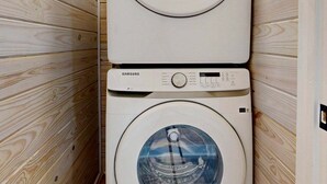 Two stacked Samsung washing machines in a wooden-paneled laundry room. - CL5 Shared Pool, Charcoal Grill, Old Town Port A (Port Aransas)