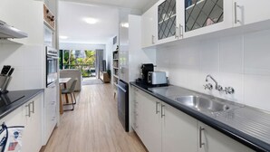 Una cocina moderna con armarios blancos, un lavamanos de acero inoxidable y un comedor con mesa y sillas.