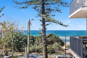 A residential area with a view of the ocean, a tall tree, and a building with a balcony. - Beachfront 2b Home. Parking. Wifi. (Broadbeach)