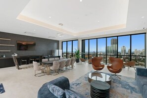 A modern living room with a dining area, large windows, and a city view. - Southport Luxury & View New 2b. Parking. Wifi. (Southport)