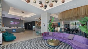 Un interior moderno con un mostrador de recepción, sofás color turquesa, un sofá modular morado y una alfombra estampada.