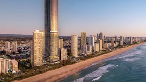 Eine Küstenstadt mit einem markanten Hochhaus, einem Strand und einer dichten Ansammlung umliegender Hochhäuser.