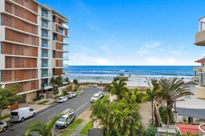A coastal hotel with multiple floors, a view of the ocean, a parking area, and palm trees. - Palm Beach 3b Apartment. Parking. Wifi. (Palm Beach)