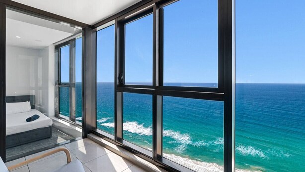 Een moderne hotelkamer met een groot balkon, een bed en uitzicht op de oceaan.