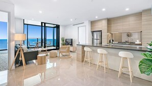 A modern kitchen with a large island, bar stools, and a view of the sea. - Stunning Beachfront level48 with parking /L (Surfers Paradise)