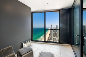 A balcony with a large window overlooking a beach and cityscape. - Sky-High Amazing Views: 2b Luxe Apartment (Surfers Paradise)