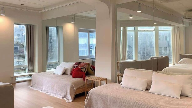 Une chambre d’hôtel moderne dotée de grandes fenêtres, d’un lit, d’une petite table et d’un coin salon.