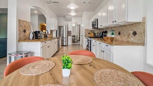 A modern kitchen with white cabinets, stainless steel appliances, and a wooden dining table with woven placemats.