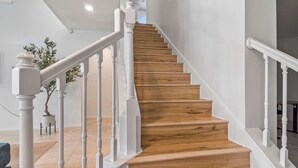 A staircase with wooden steps and white balusters, leading to a landing with a potted plant.