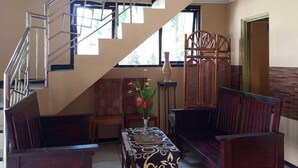 A spacious living area with a staircase, wooden furniture, and a decorative table. - Hotel Prima Asri 153 (Batu)