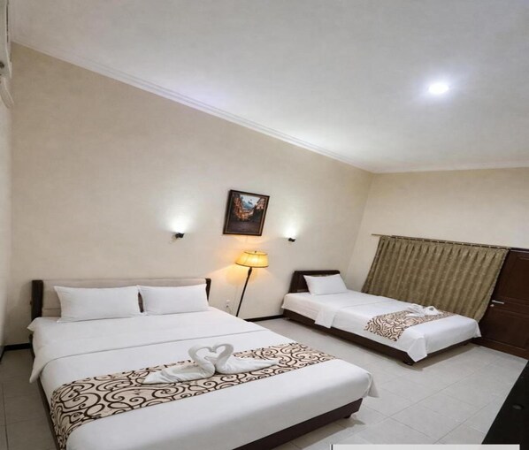 Una habitació d'hotel amb dos llits, un quadre a la paret, una làmpada i una cortina.