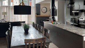 A modern kitchen with a wooden dining table, dark cabinetry, and a large island.
