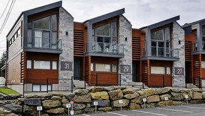 A modern building with numbered units, stone facade, and a parking area.