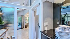 A modern bathroom with a glass shower enclosure, a towel stack, and a potted plant. - Cape Cod Home in Woodstock, Pet-Friendly & Wooded (Woodstock)