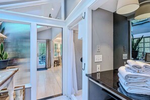 A modern bathroom with a glass shower enclosure, a towel stack, and a potted plant. - Cape Cod Home in Woodstock, Pet-Friendly & Wooded (Woodstock)