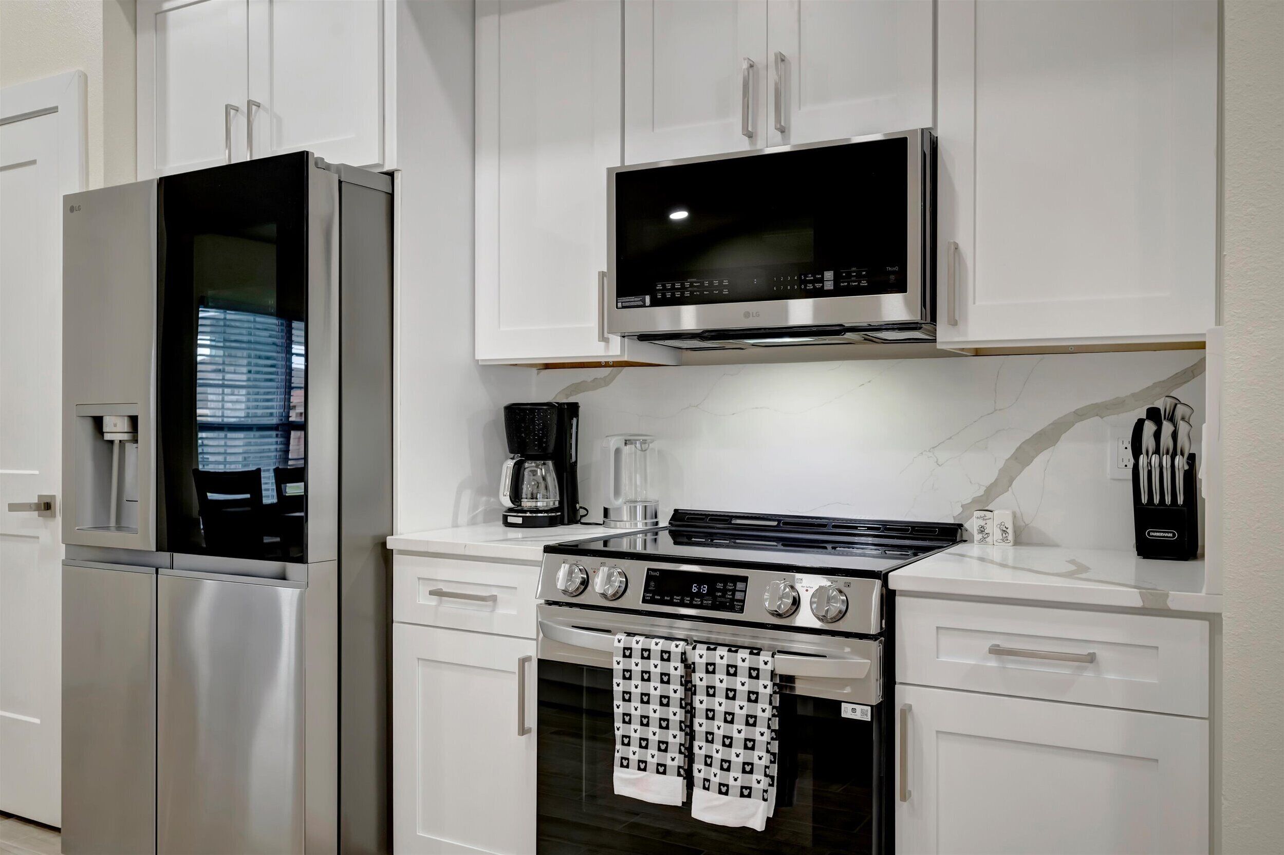 Une cuisine moderne équipée d’appareils électroménagers en acier inoxydable, notamment un réfrigérateur, un four à micro-ondes et une cuisinière.