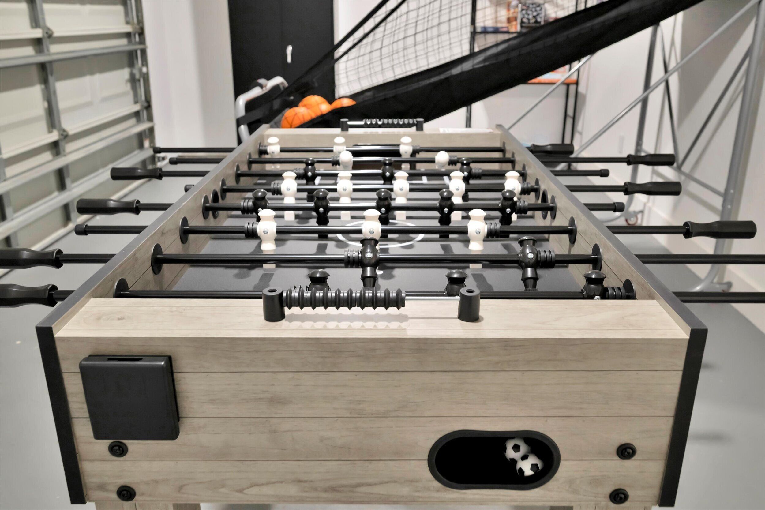 A foosball table with a wooden base and black rods.