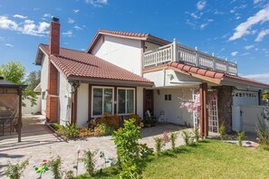 A two-story house with a balcony, a chimney, and a garden with various plants and flowers. - Terrific 4-bedroom house with AC in West Covina (West Covina)