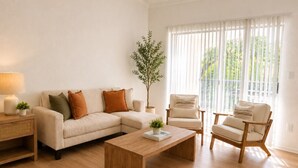 A living room with a sofa, two chairs, a coffee table, a lamp, and a plant.