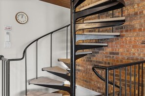 Eine Wendeltreppe vor einer Ziegelwand, mit einer Uhr und einer Steckdose.