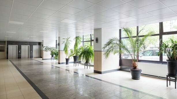 A spacious indoor area with a tiled floor, large windows, and potted plants. - Metro Świętokrzyska Simple Studio (Warszawa)