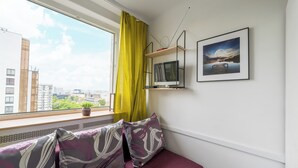 A room with a window, a bed, a mounted TV, a framed picture, and a potted plant. - Metro Świętokrzyska Simple Studio (Warszawa)