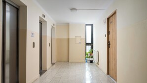 A hallway with doors, a sign, a window, and a radiator. - Metro Świętokrzyska Simple Studio (Warszawa)