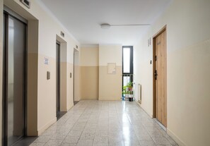A hallway with doors, a sign, a window, and a radiator. - Metro Świętokrzyska Simple Studio (Warszawa)