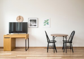 Ein modernes Zimmer mit einem Holztisch, einem Fernseher, zwei Stühlen und Bildern an der Wand.