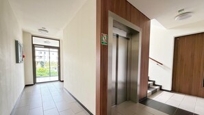 Un pasillo moderno con una pared de acento de madera, una puerta de vidrio que da al exterior y una escalera con barandilla de madera.