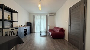 Un espacio de estar con sofá, una mesa de comedor, un televisor y una estantería.