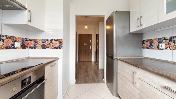 Una cocina moderna con armarios de madera, un refrigerador de acero inoxidable y un salpicadero de azulejos.