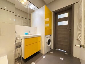 Ein modernes Badezimmer mit Waschbecken, Spiegel, Handtuchhalter und einer Waschmaschine.