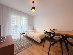 Ein modernes Schlafzimmer mit Bett, Nachttisch und Schreibtischbereich mit Stühlen.