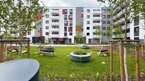 En moderne bygning med flere altaner, en velholdt græsplæne og udendørs siddeområder.