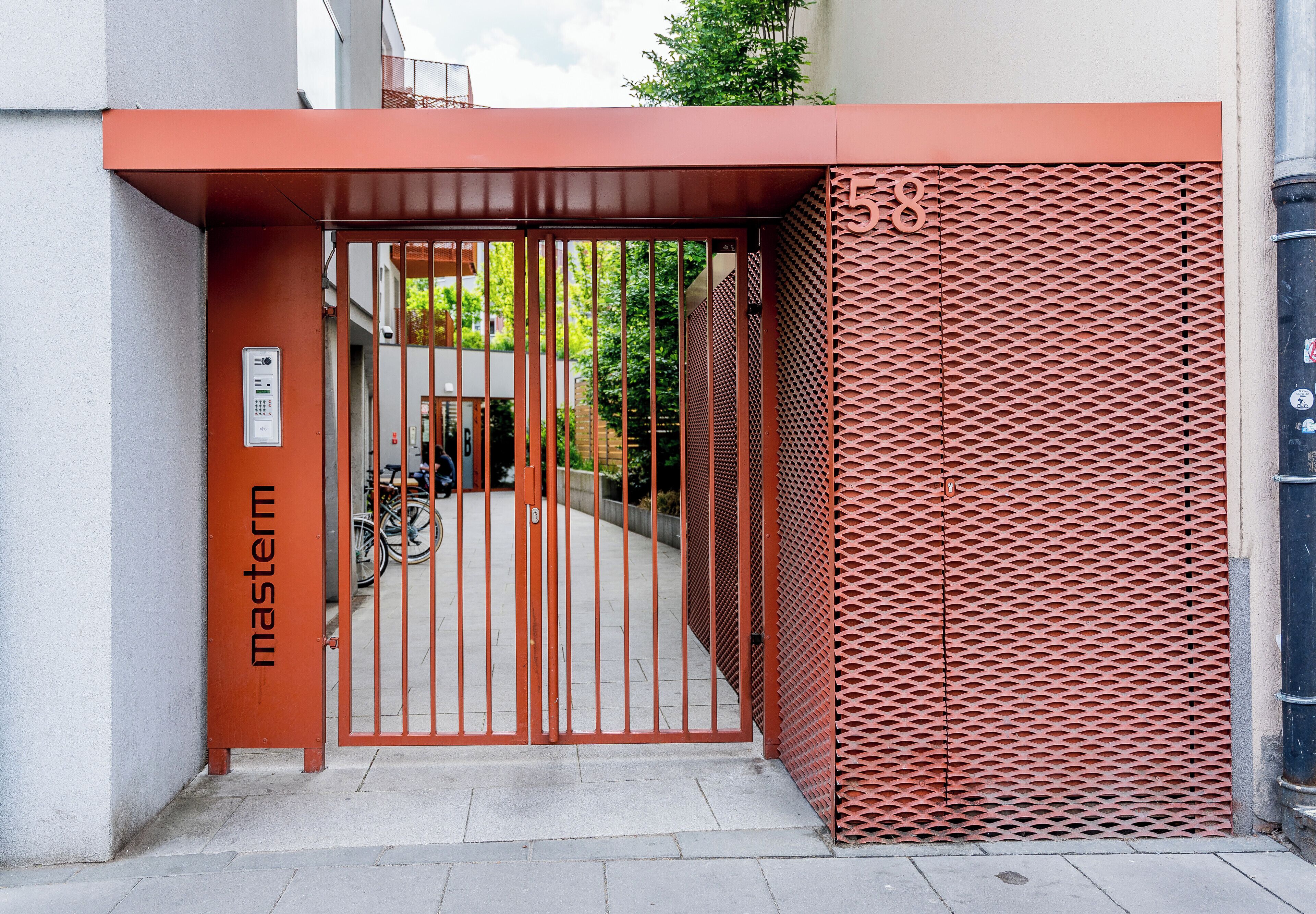 Ein verschlossener Eingang mit einem Schild, das 'Master' zeigt, ein Metallgitter und eine strukturierte Wand.