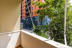 A balcony with a view of a red brick building and greenery. - The Homey Flat Stylish 2BR City Apartment (Tirana)