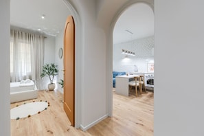 A modern living room with a sofa, a dining area with a table and chairs, and a kitchen with white brick backsplash. - The Homey Flat Stylish 2BR City Apartment (Tirana)