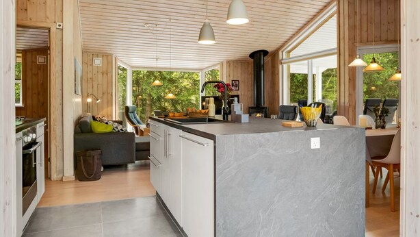 Eine moderne Küche mit einer zentralen Kochinsel, Holzvertäfelung und großen Fenstern.