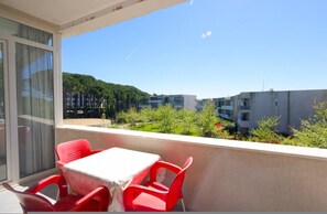 Een balkon met een tafel en stoelen, uitzicht op een woongebied met gebouwen en bomen.