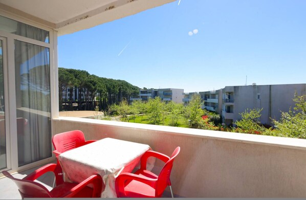 Een balkon met een tafel en stoelen, met uitzicht op een woonwijk met gebouwen en bomen.