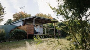 A house with a covered porch, a garage, and a small garden area. - Tully Cottage - a home among the gum trees (Break O'Day)