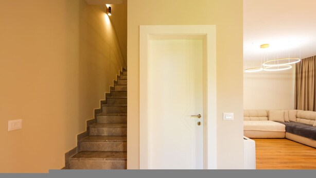 A staircase leading to a door, a living room with a sofa and a modern light fixture. - Sanpietro Vacation Villa 014 (Ishëm)